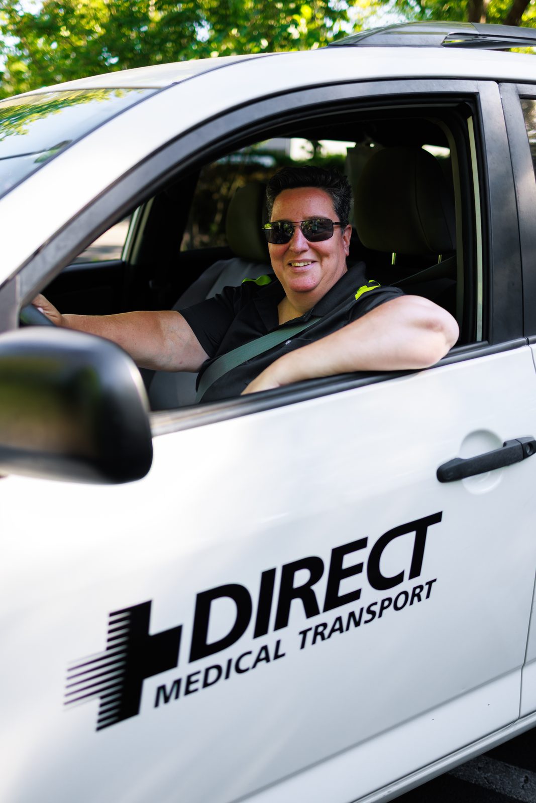 Smiling Direct Medical Transportation driver at the wheel of a branded medical transportation vehicle in Eugene, Oregon